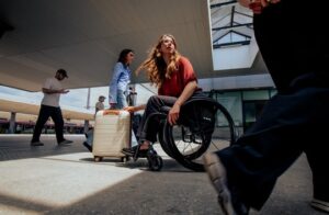 Rollstuhlfahrerin mit Koffer auf reisen